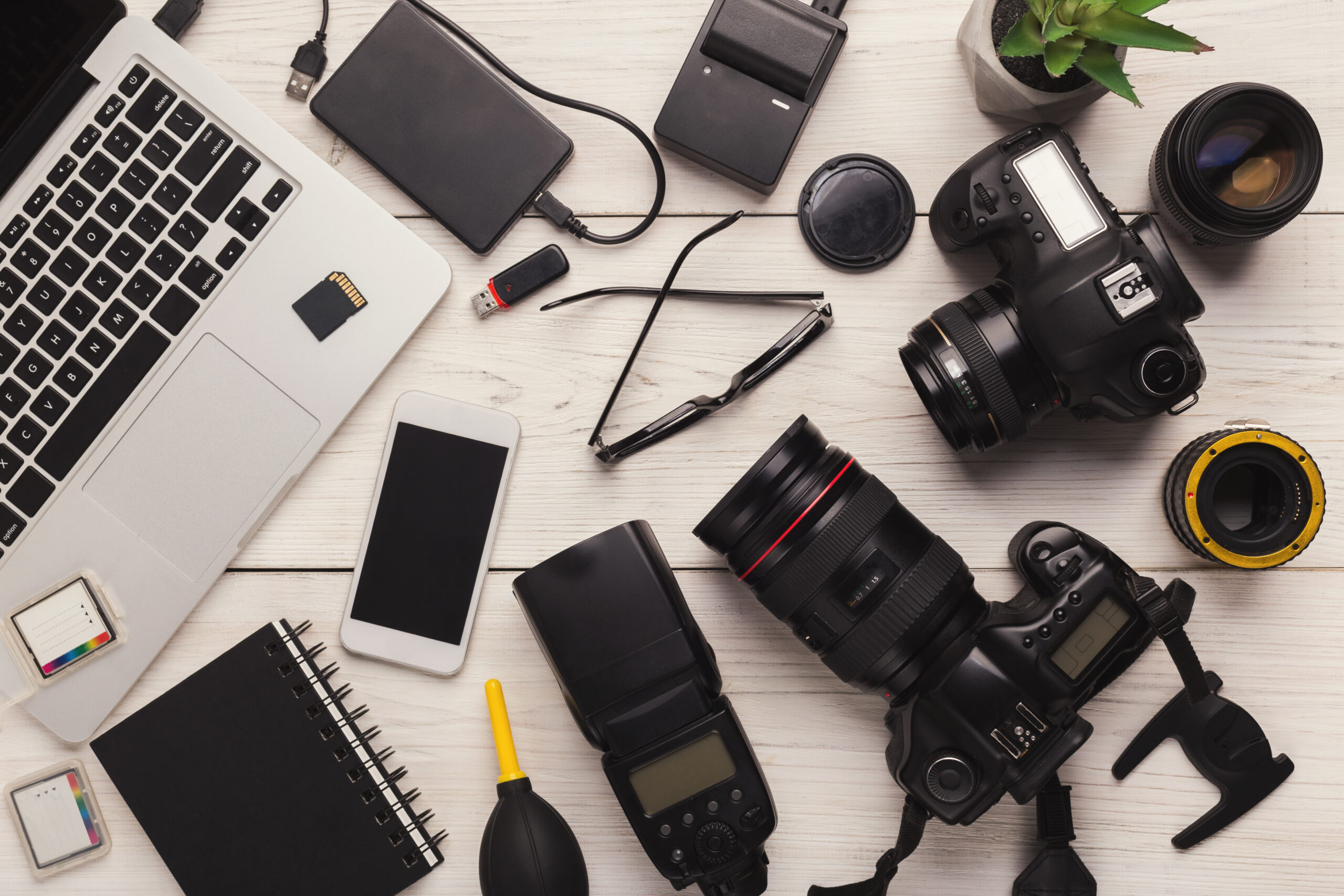 Set of modern photographic equipment on white wooden table, top view. Professional tools of creative designer, photographer workplace background